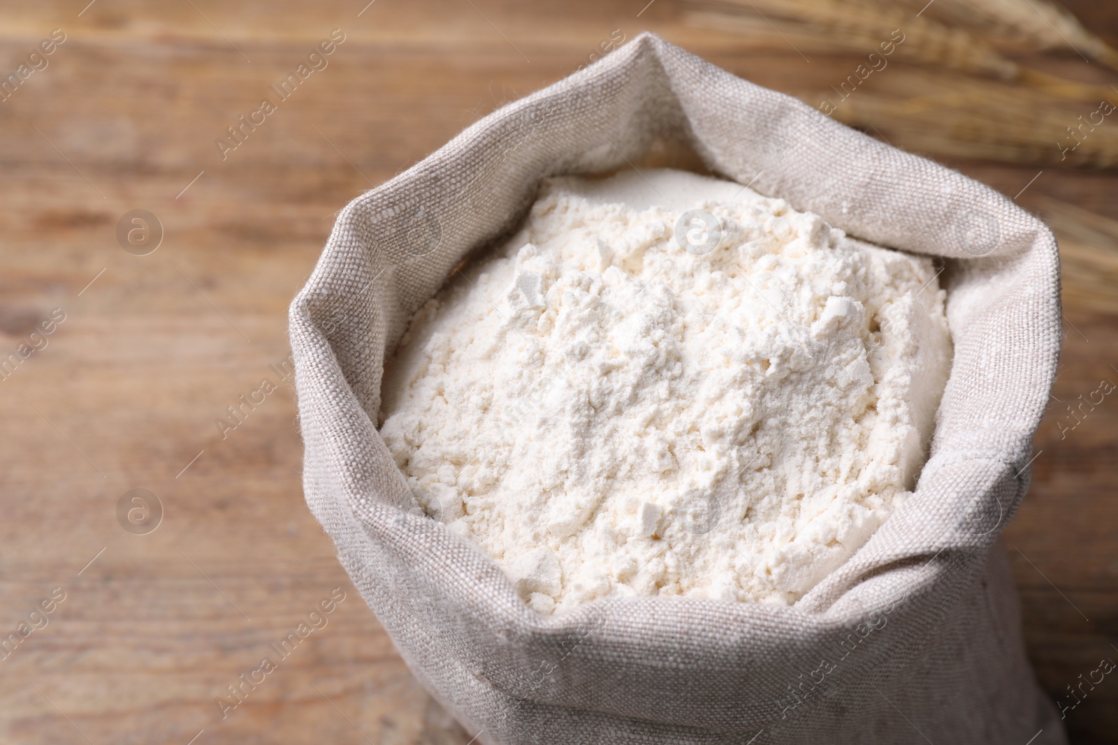 Photo of Sack with flour on wooden background, above view