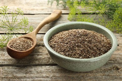 Photo of Dry seeds and fresh dill on wooden table