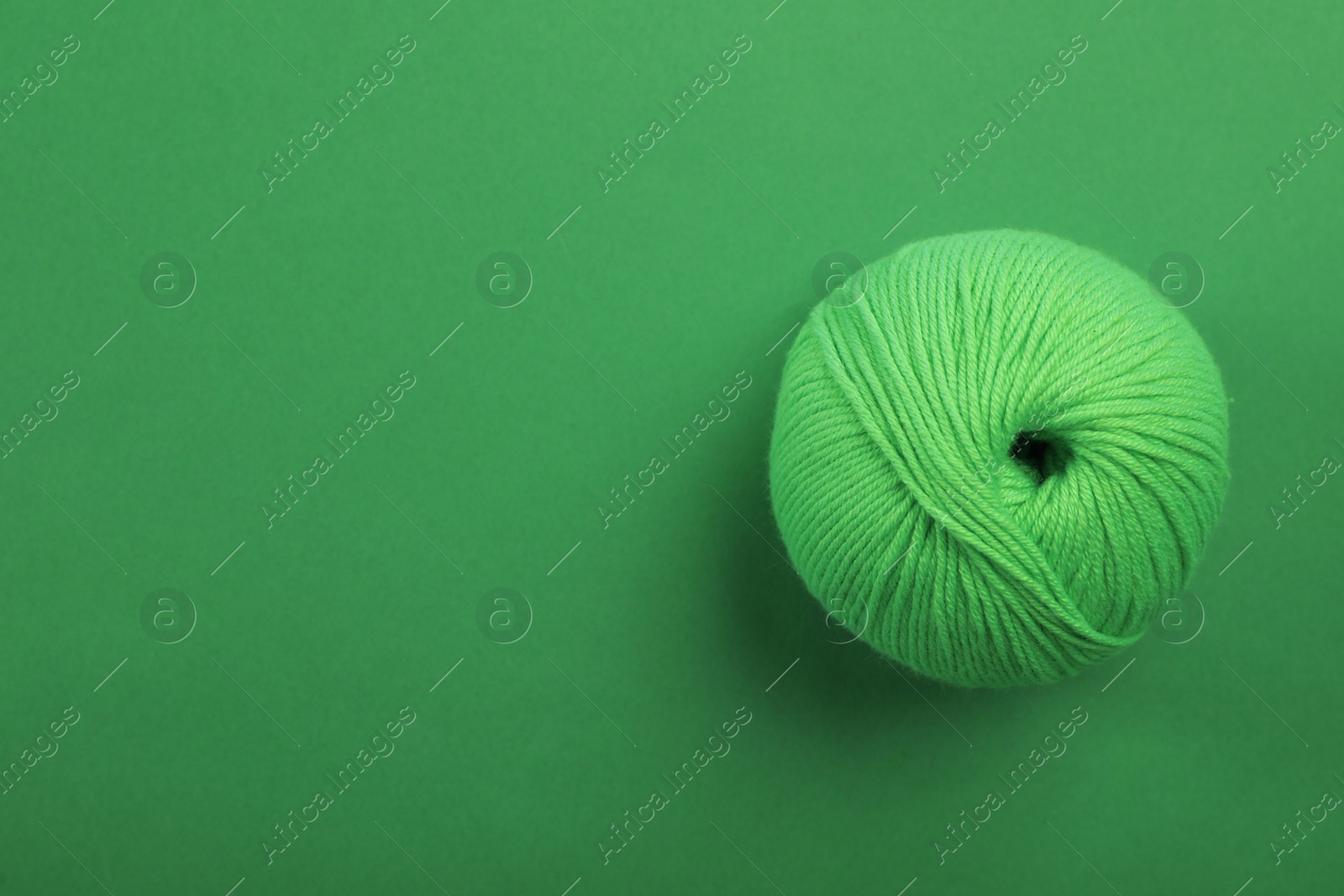 Photo of Soft woolen yarn on green background, top view. Space for text