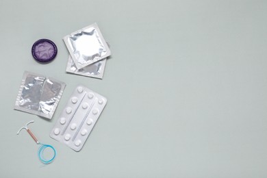 Contraceptive pills, condoms and intrauterine device on light grey background, flat lay and space for text. Different birth control methods