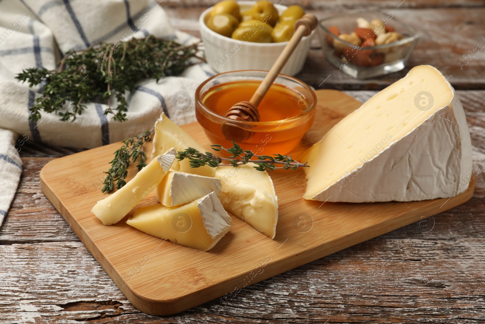 Photo of Tasty Camembert cheese with thyme and honey on wooden table