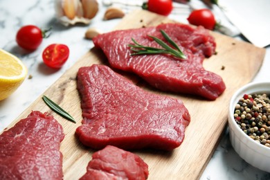 Fresh raw meat steaks and spices on white table, closeup