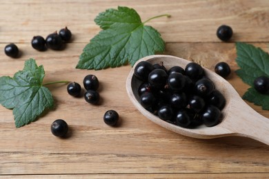 Ripe blackcurrants and leaves on wooden table, closeup