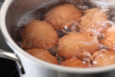 Chicken eggs boiling in pot, closeup view