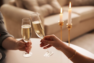 People clinking glasses with champagne at home, closeup