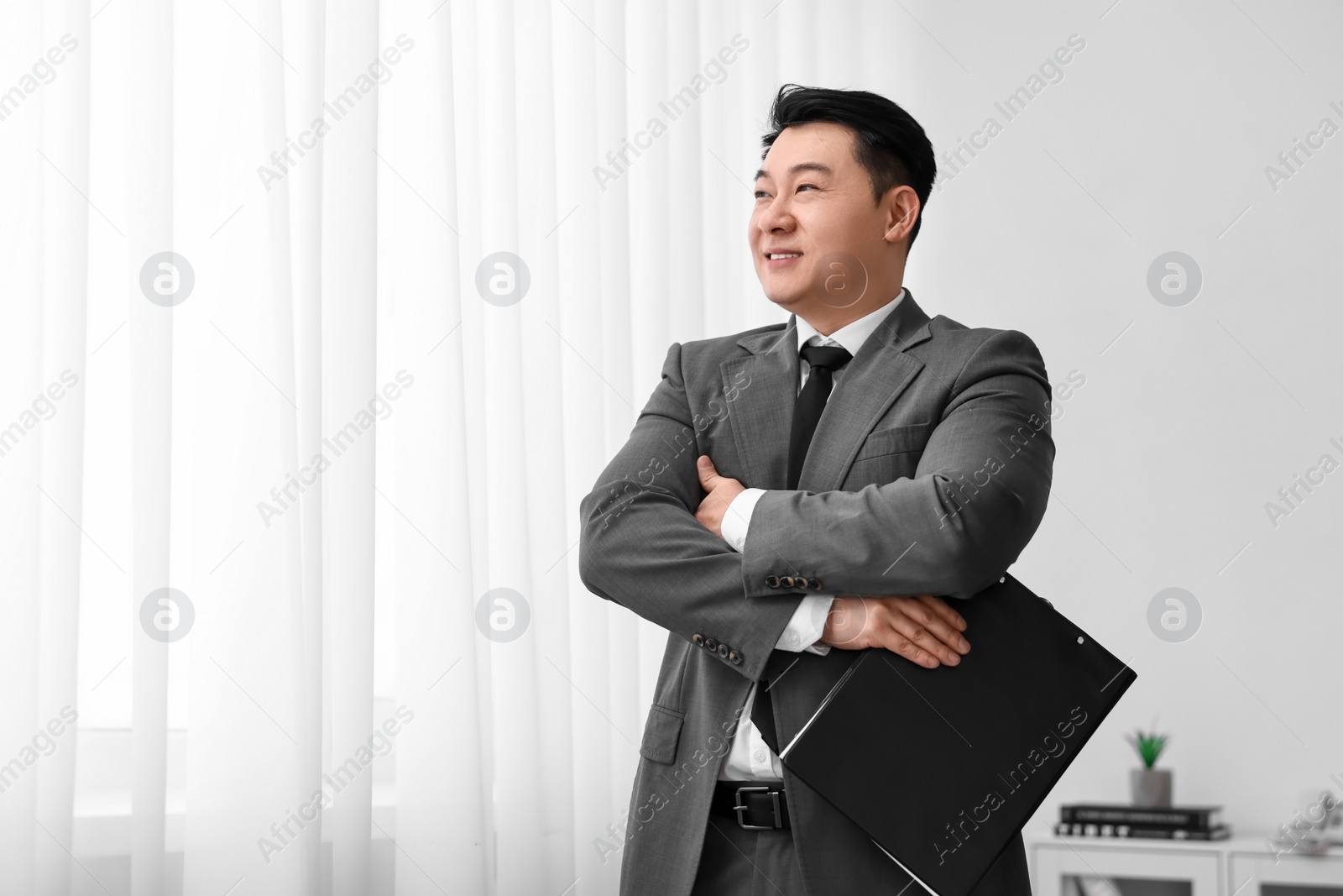 Photo of Portrait of happy notary with clipboard indoors, space for text