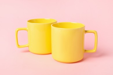 Two yellow ceramic mugs on pink background