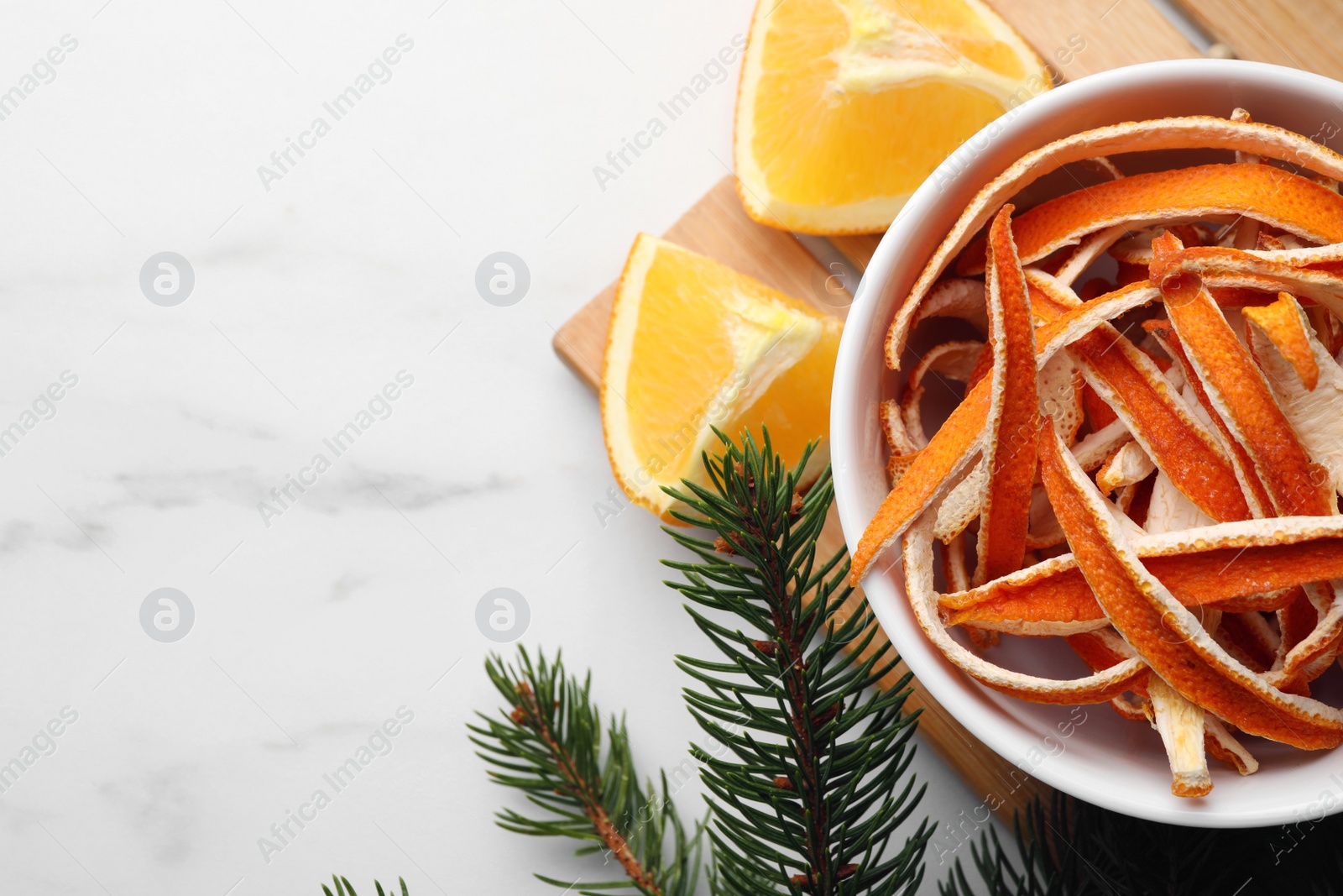 Photo of Dry peels, oranges and fir branch on white marble table, flat lay. Space for text