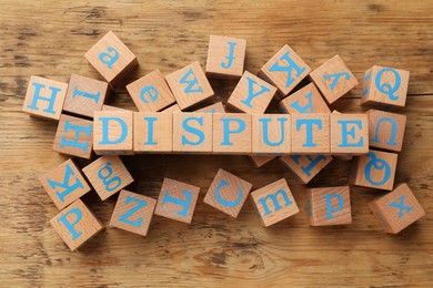 Photo of Cubes with word Dispute on wooden table, flat lay