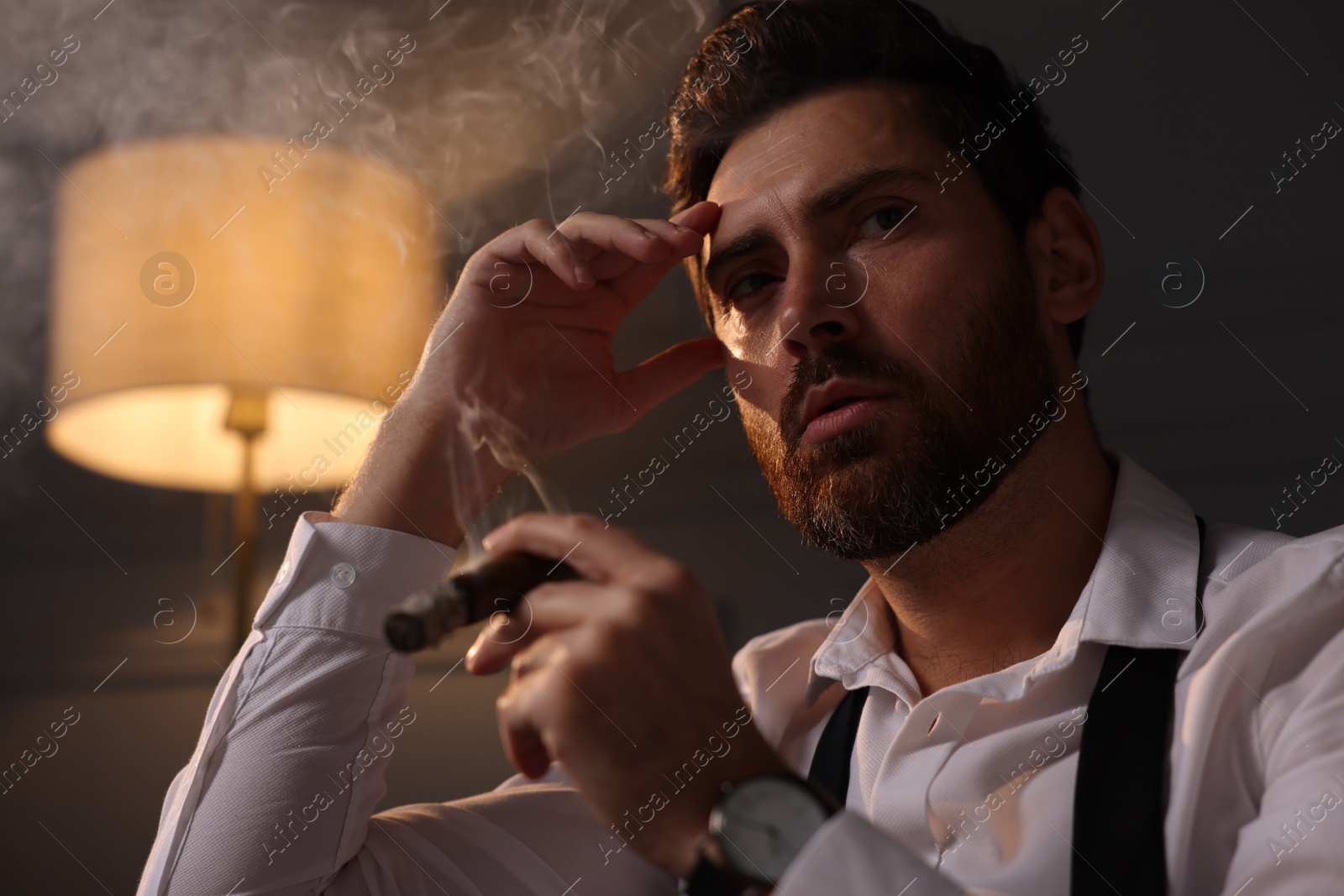 Photo of Handsome man smoking cigar at home in evening