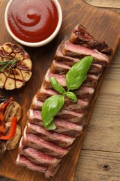 Photo of Delicious grilled beef steak with spices and tomato sauce on wooden table, top view