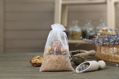 Scented sachet with dried roses on wooden table