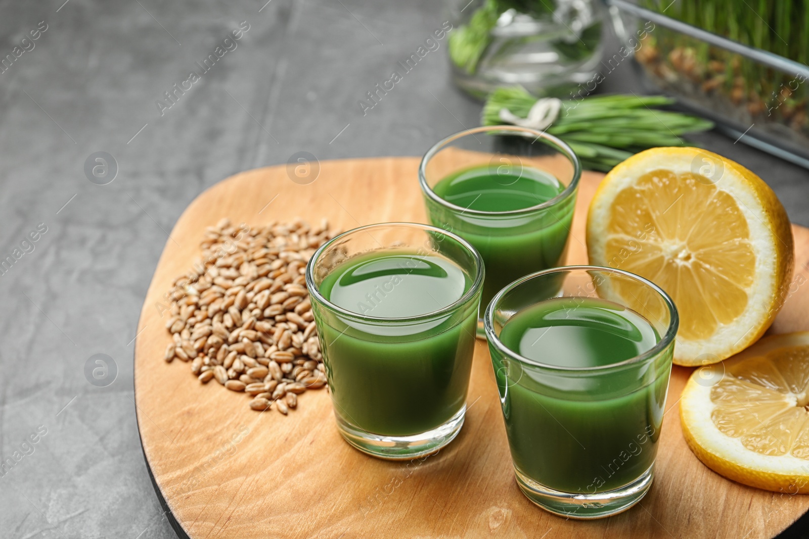 Composition with glasses of wheat grass juice and lemon on grey stone background. Space for text Photo of Composition with glasses of wheat grass juice and lemon on grey stone background. Space for text