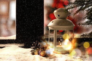 Image of Lantern with candle and pine cones near window outdoors. Christmas eve