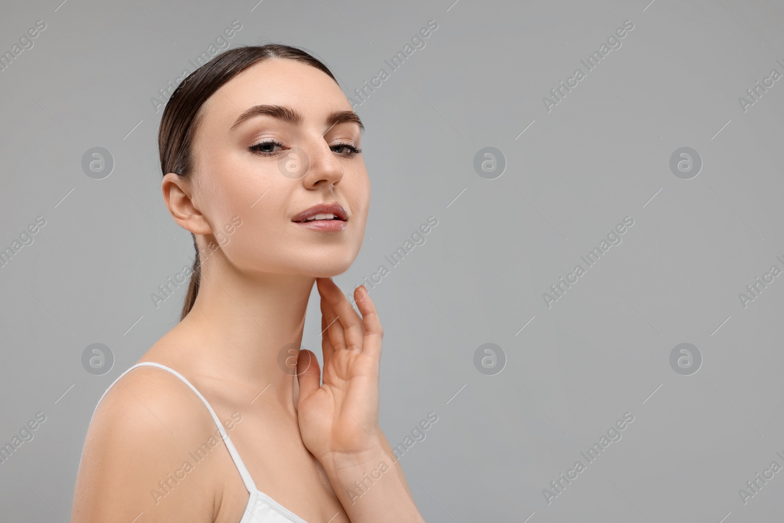 Photo of Beautiful woman touching her neck on grey background. Space for text