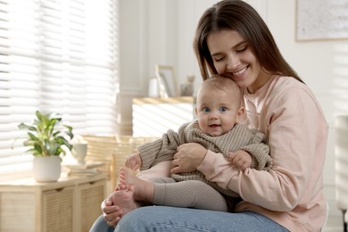 Photo of Happy young mother with her baby at home. Space for text