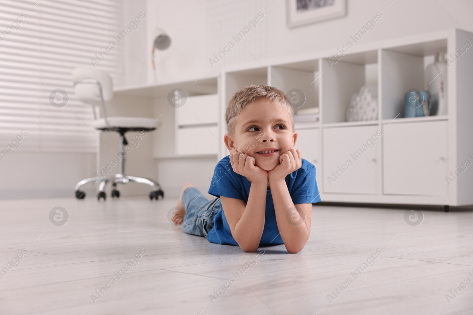 Photo of Cute little boy lying on warm floor at home. Heating system