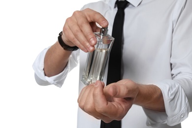 Man applying perfume on wrist against white background, closeup