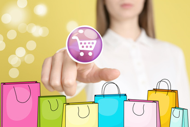 Image of Online shopping. Woman touching button with cart illustration on virtual screen with paper bags, closeup