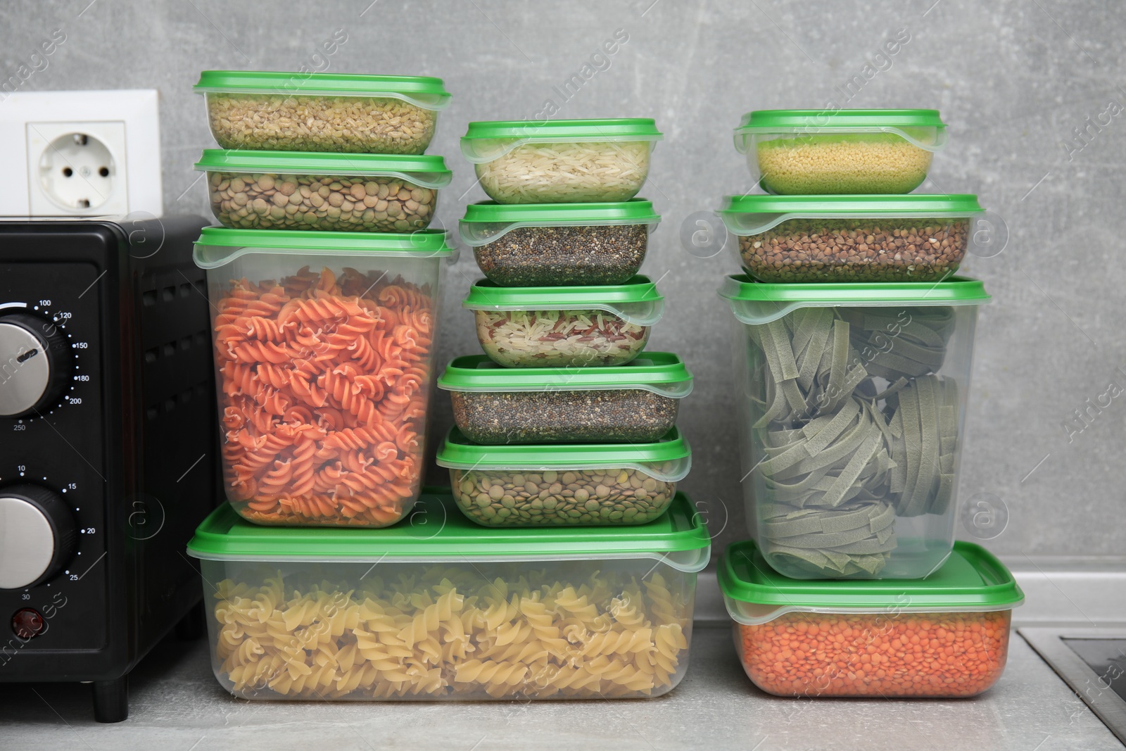 Photo of Plastic containers filled with food products on grey table in kitchen