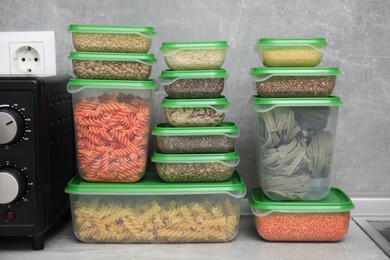 Photo of Plastic containers filled with food products on grey table in kitchen