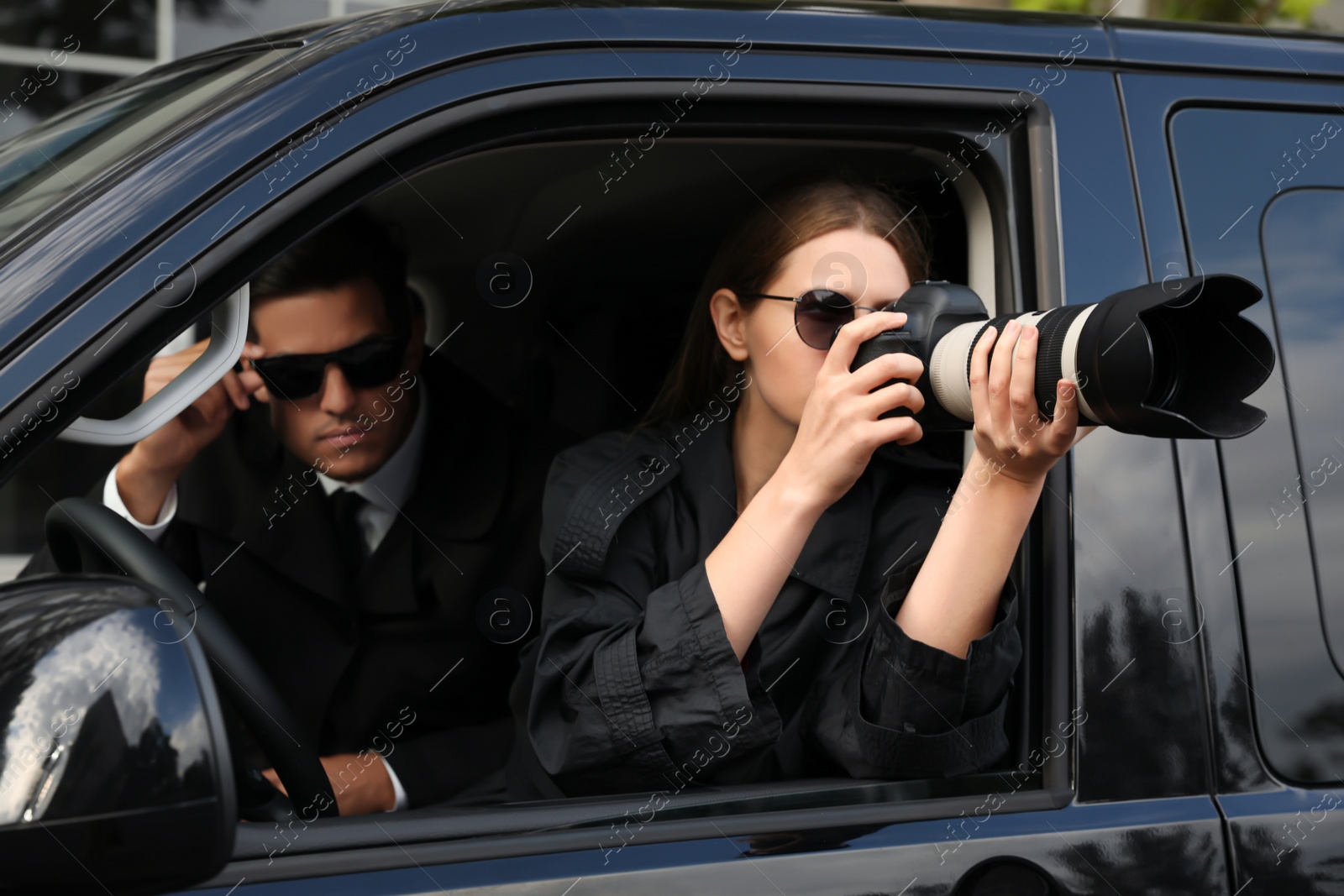 Photo of Private detectives with modern camera spying from car