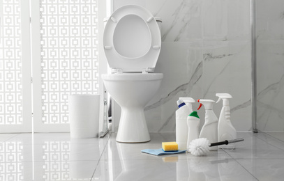 Photo of Toilet bowl and cleaning supplies in modern bathroom