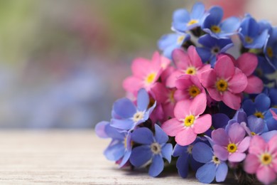 Photo of Beautiful Forget-me-not flowers on white wooden table, closeup. Space for text