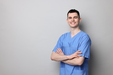 Photo of Portrait of smiling medical assistant with crossed arms on grey background. Space for text