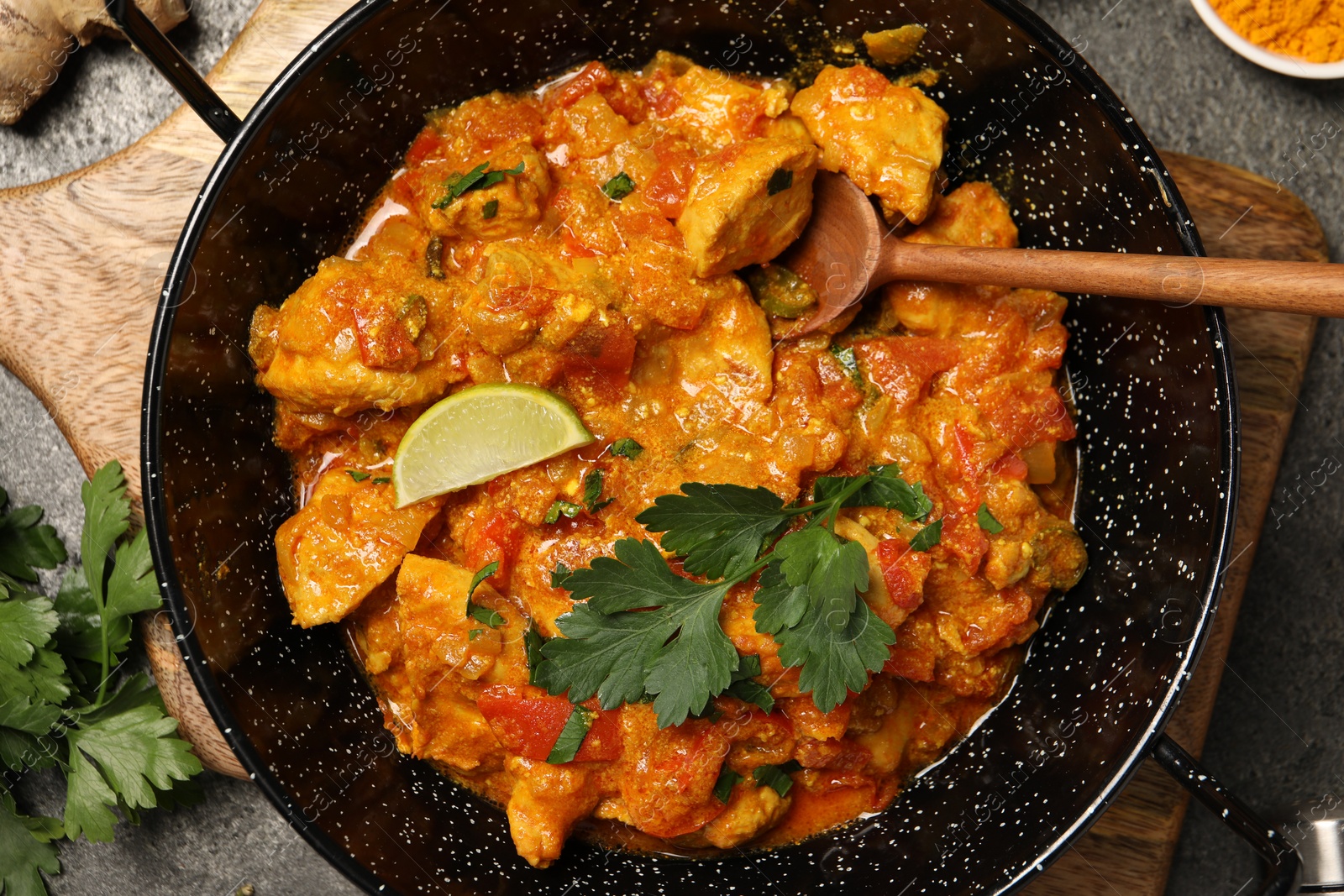 Photo of Delicious chicken curry in frying pan on grey table, top view