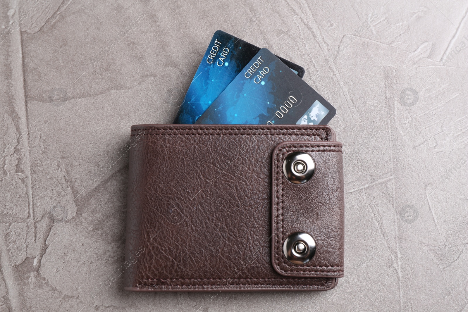 Photo of Credit cards in leather wallet on grey textured table, top view