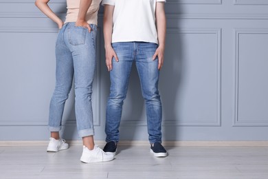 Photo of People in stylish jeans near light grey wall indoors, closeup