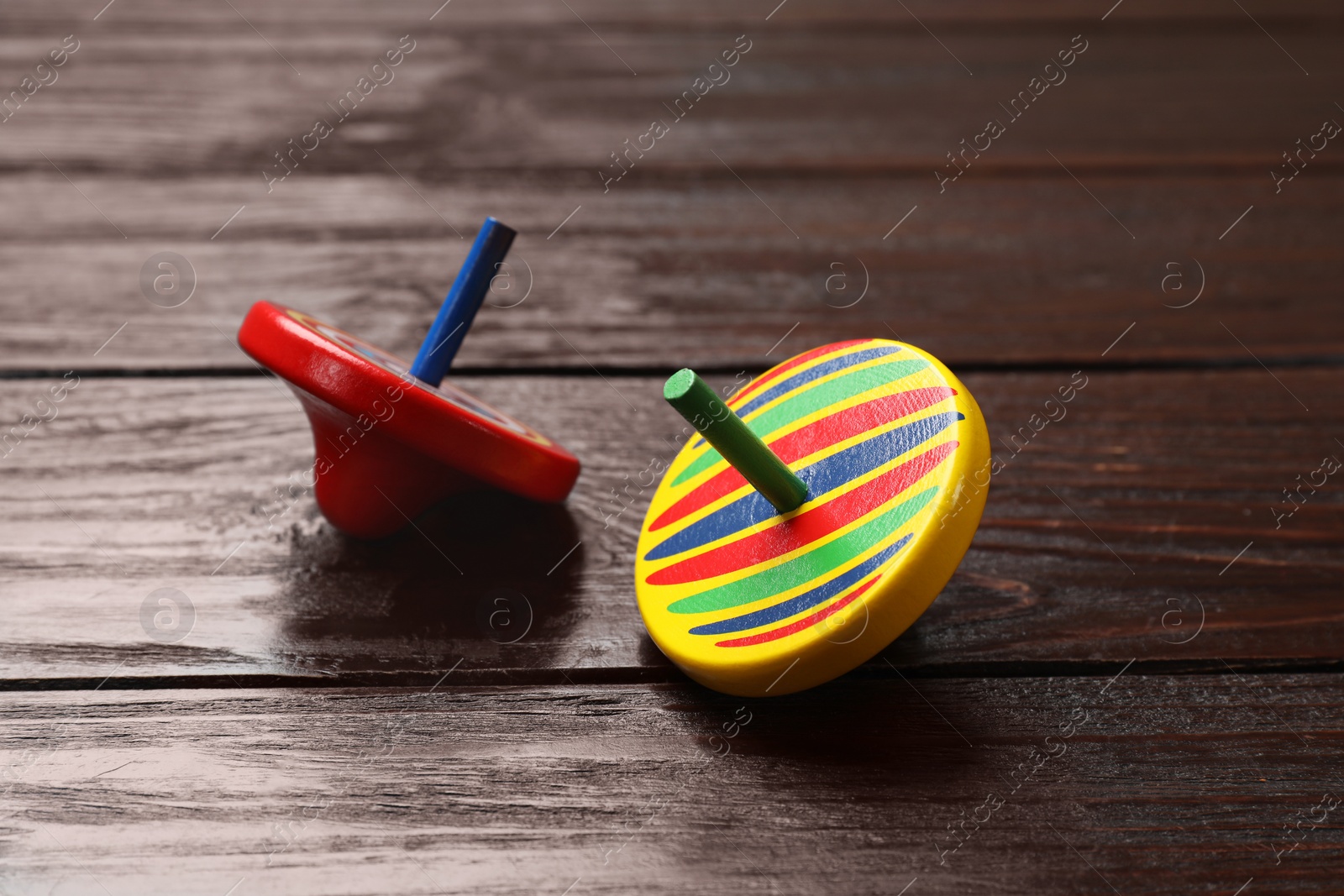 Photo of Bright spinning tops on wooden table, closeup