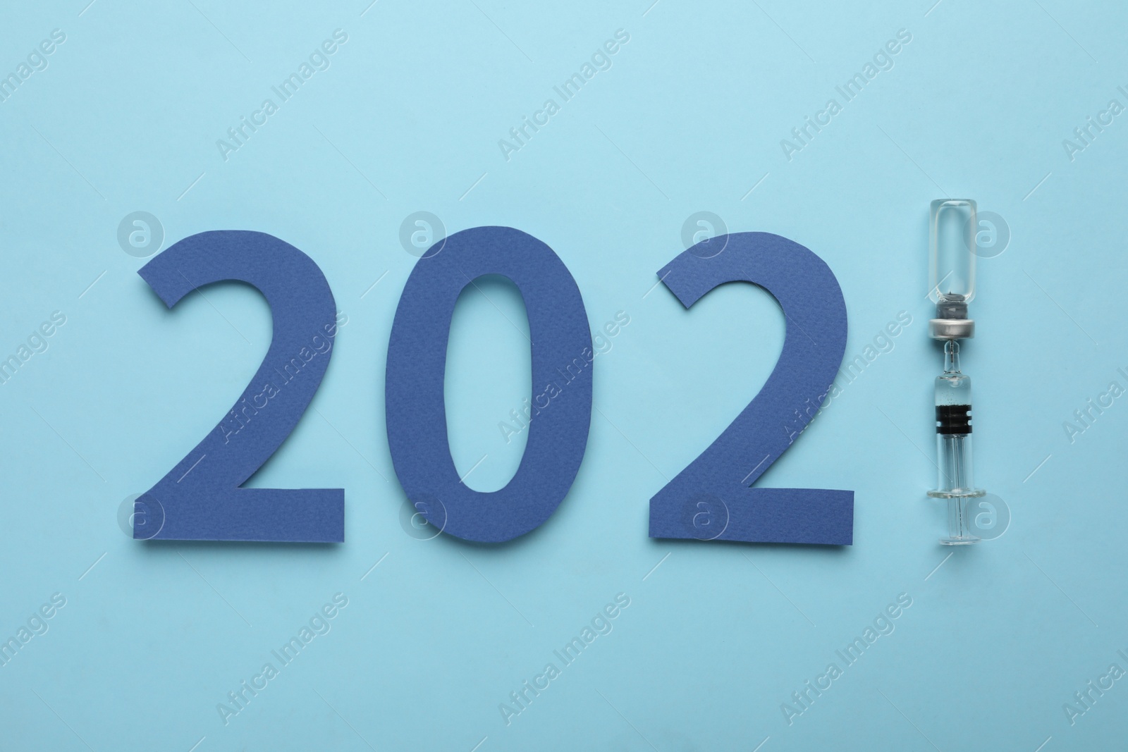 Photo of Paper numbers, syringe and vial with coronavirus vaccine forming 2021 on light blue background, flat lay