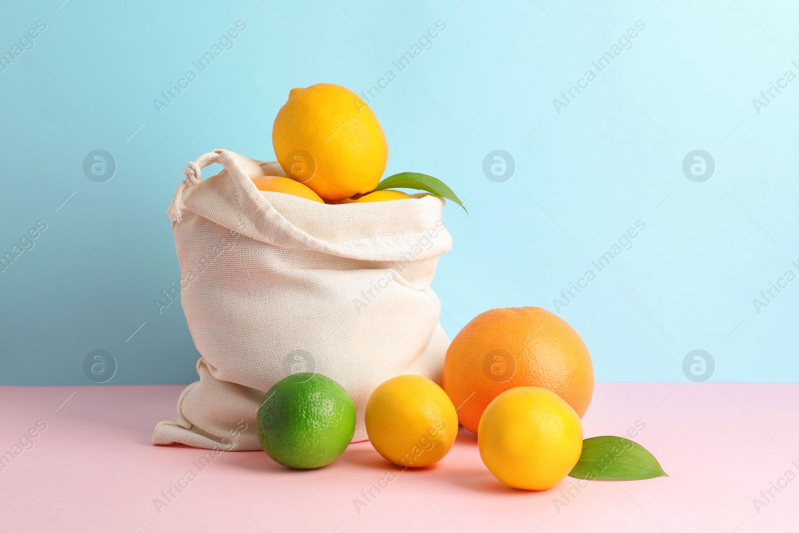 Photo of Cotton eco bag with citrus fruits on color background