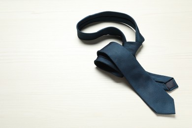 Photo of One blue necktie on white wooden table. Space for text