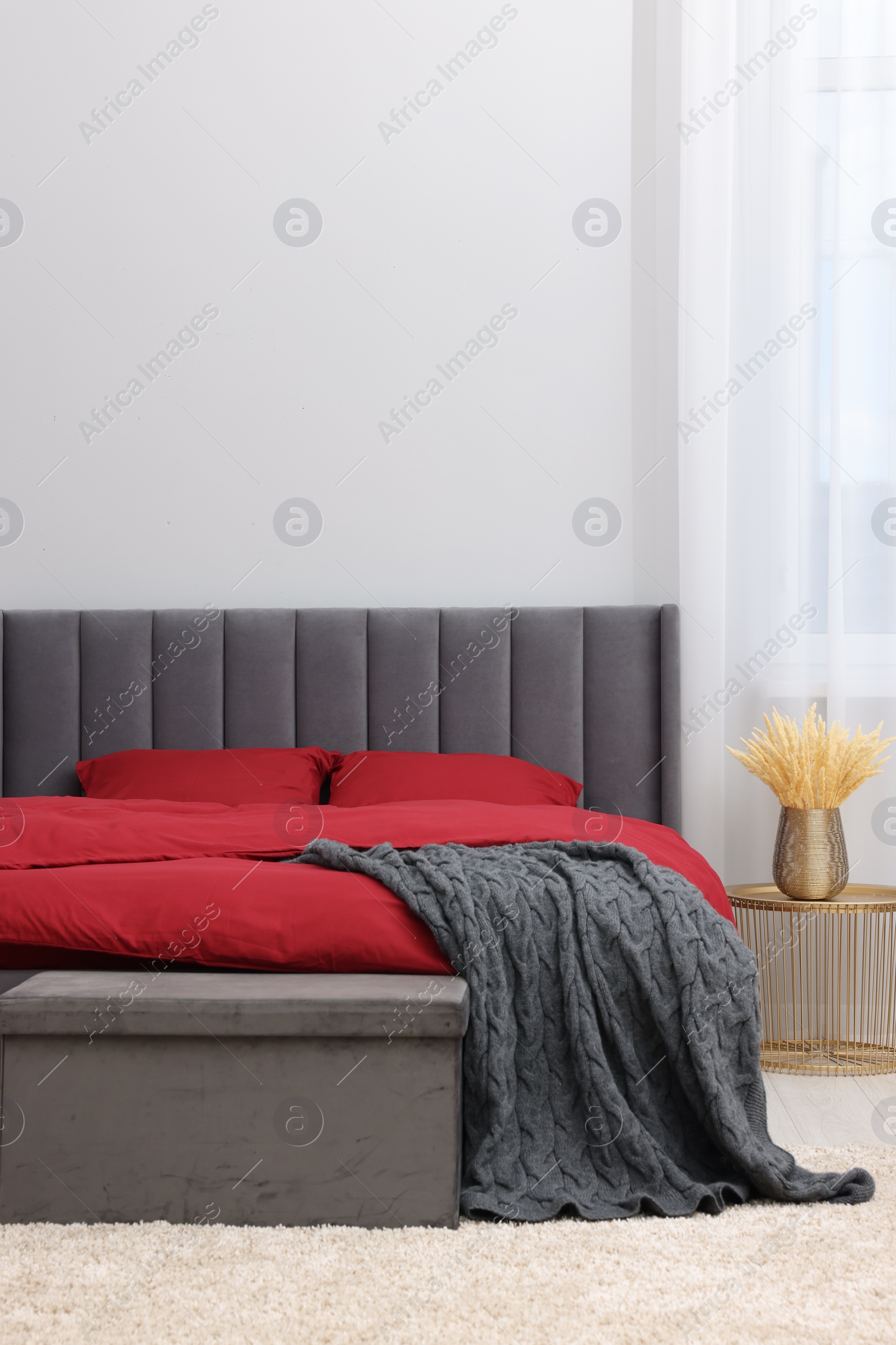 Photo of Stylish bedroom with comfortable bed and decorative plants in vase on table. Interior design