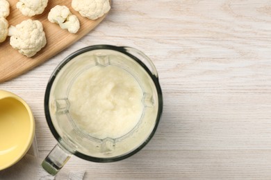 Photo of Baby food. Blender with delicious cauliflower puree on light wooden table, flat lay and space for text