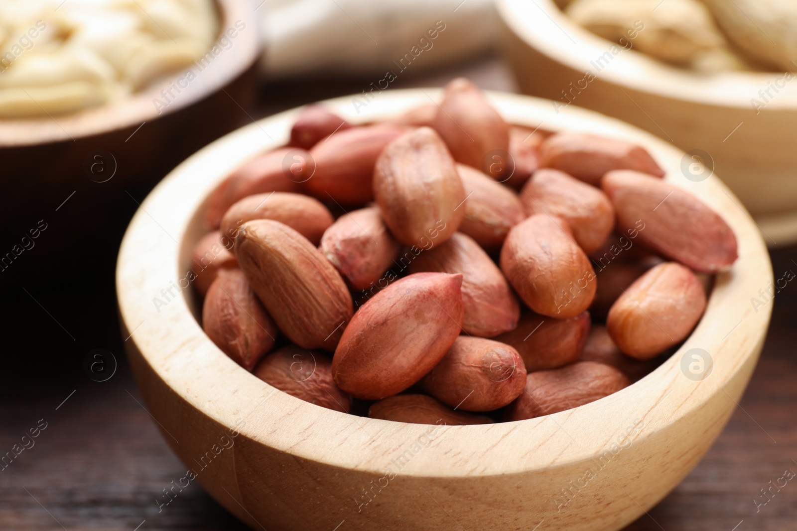 Photo of Fresh peanuts in bowl on wooden table, closeup