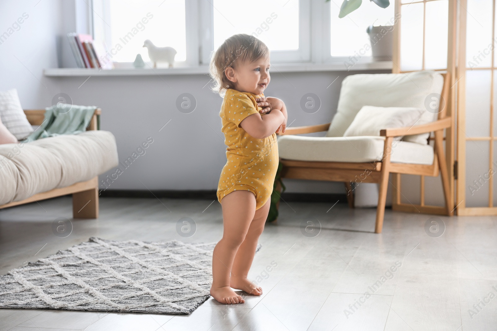 Photo of Cute baby learning to walk in living room