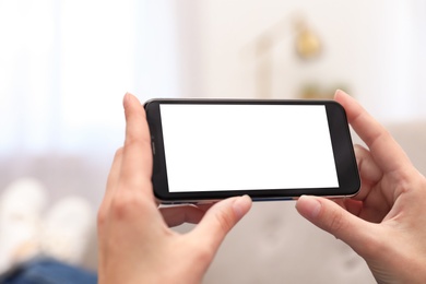 Photo of Woman holding smartphone with blank screen indoors, closeup of hands. Space for text