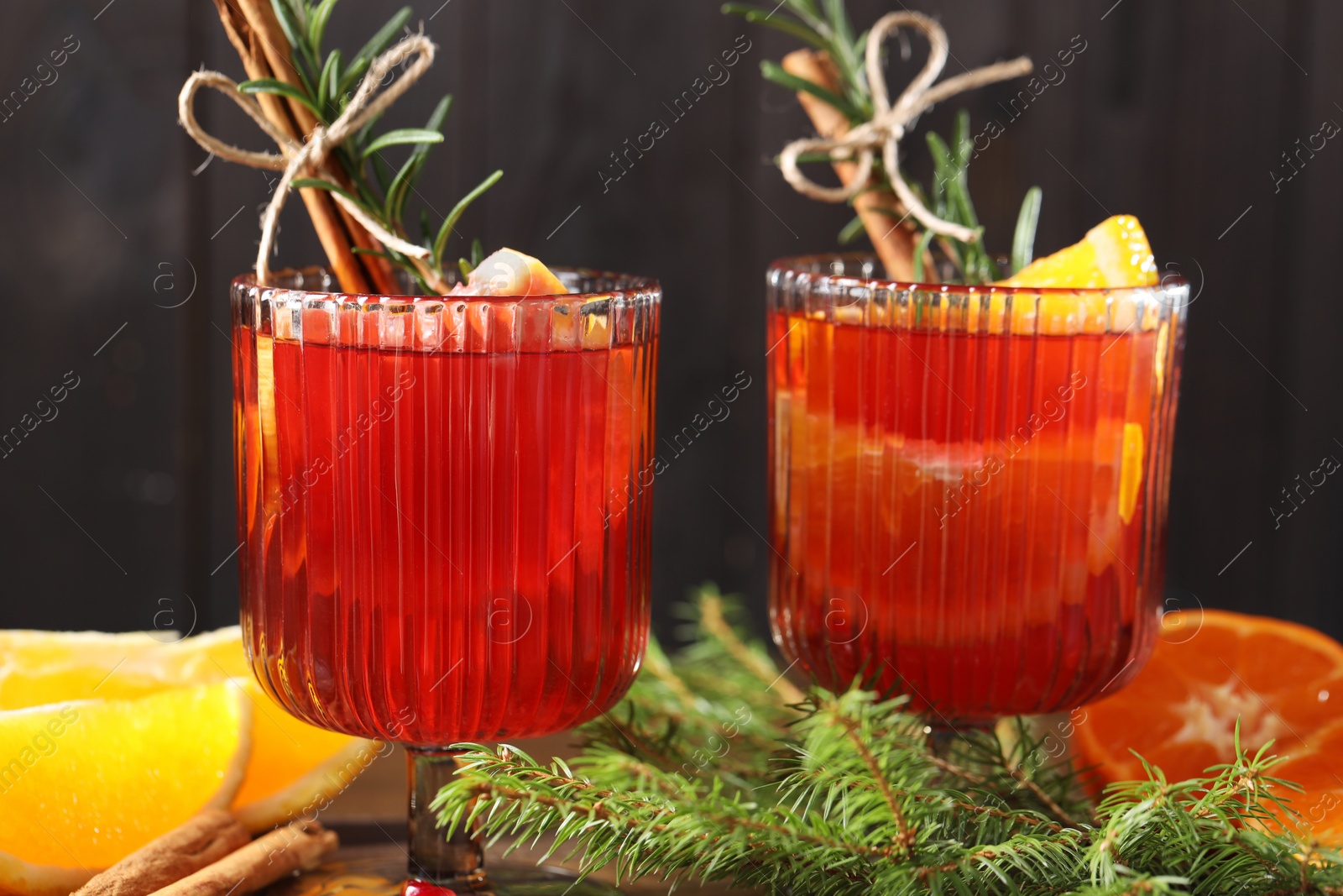 Photo of Christmas Sangria cocktail in glasses, ingredients and fir tree branches on table, closeup