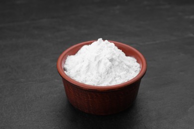 Photo of Bowl of natural starch on black table, closeup