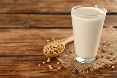 Photo of Glass with fresh soy milk and grains on wooden table. Space for text