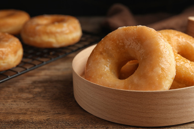 Photo of Delicious donuts in box on wooden table, closeup
