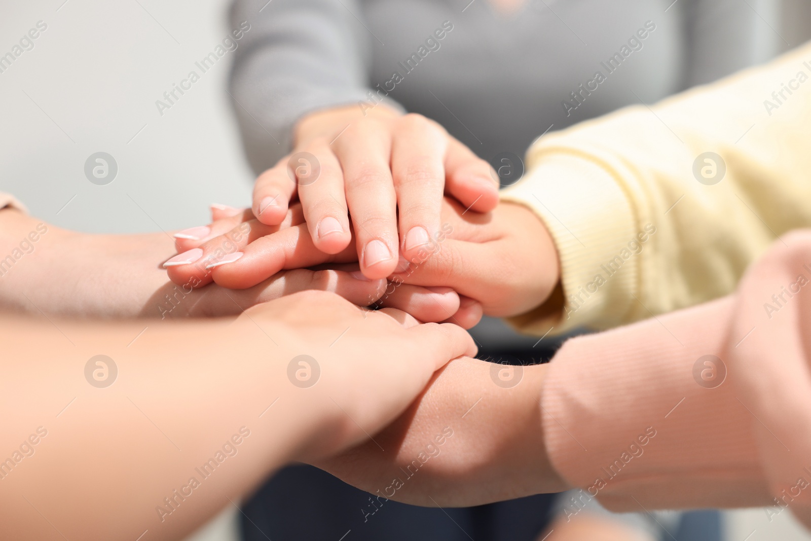 Photo of Group of people holding hands together indoors, closeup. Unity concept