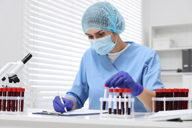 Laboratory testing. Doctor with blood samples in tubes at white table indoors