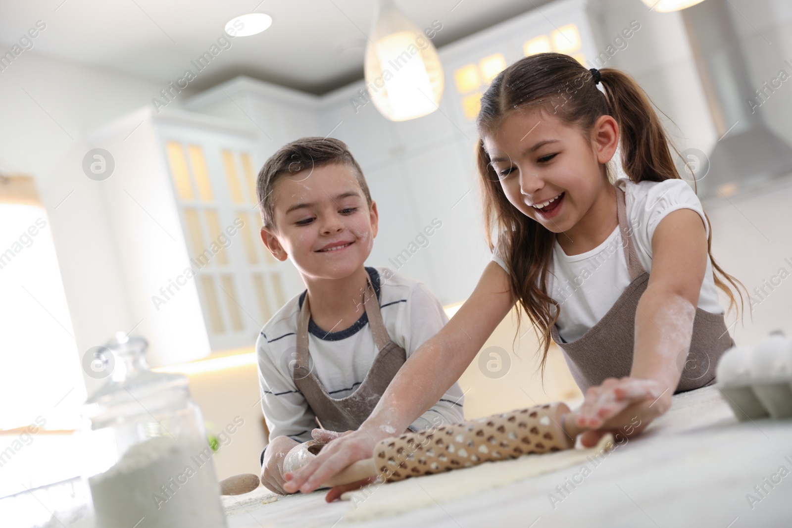 Photo of Cute little children cooking dough together in kitchen