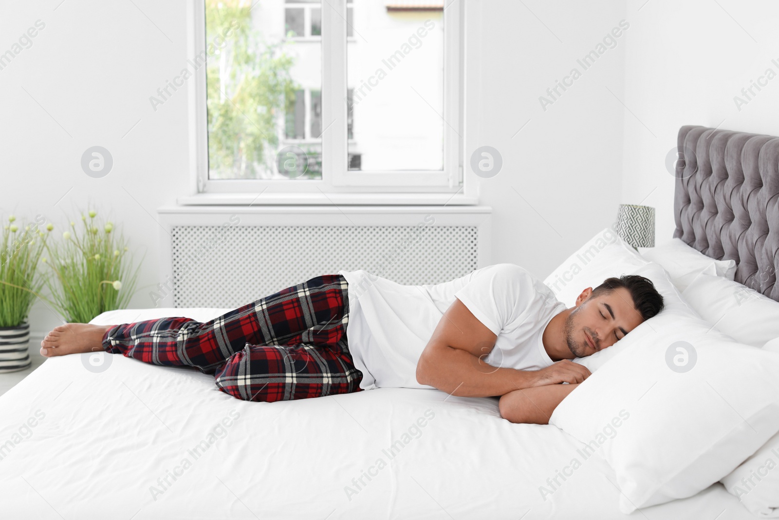 Photo of Young man sleeping on bed with soft pillows at home