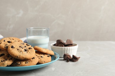 Photo of Plate with delicious chocolate chip cookies on grey marble table. Space for text